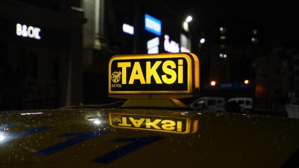 A glowing taxi sign at night with a blurred urban backdrop.